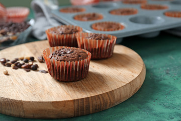 Board with tasty chocolate muffins on table