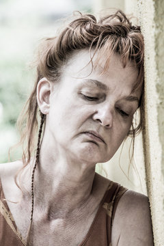 a woman resignedly leans her head against a wall