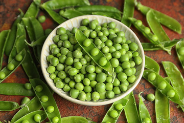 Bowl with green peas on table
