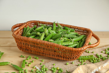 Basket with green peas on wooden table