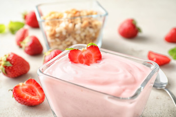 Bowl with tasty strawberry yogurt on light table