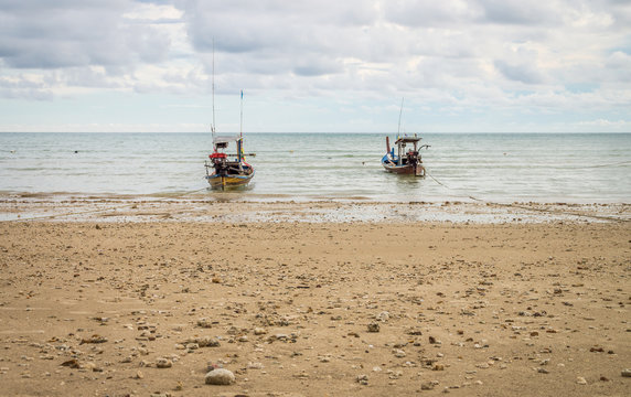 Two traditional Thai fishing boat anchored on a beach. Seascape view of Andaman sea from Thailand.