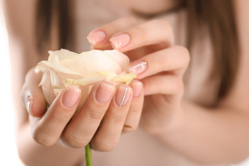 Young woman with beautiful manicure holding rose, closeup