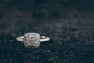 Engagement ring with gemstones on dark background with copy space.