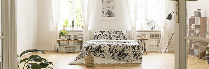 Panorama of a minimalist, spacious bedroom interior with wooden furniture and a comfy double bed.