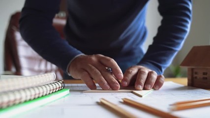 Concept architects. Engineer with pencil draw the architects objects on a blueprint in the office. 4K video with shallow depth of field focus on hands.