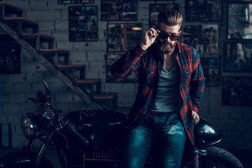 Young Biker in Sunglasses on Motorcycle in Garage.