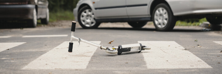 Drunk driving concept. Fatal aftermath of a car accident - a kid's scooter lying on an empty road...