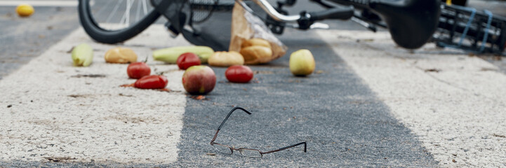 Glasses, groceries and a bicycle on an empty road crossing - panorama of a dangerous car accident...