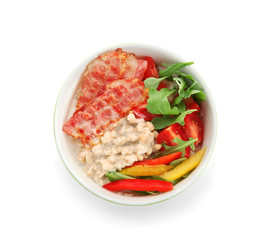 Bowl with delicious oatmeal, bacon, herbs and vegetables on white background