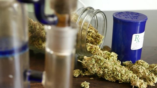SLIDE LEFT Marijuana buds in glass Rx jar for recreational or prescription medicinal weed smoking.