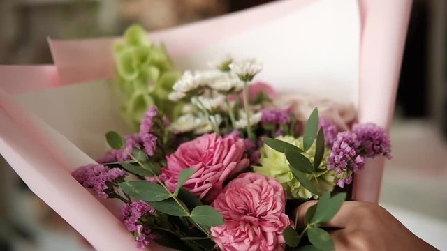 woman florist making bouquet of pink flowers indoor. Female florist preparing bouquet of roses and carnation in flower shop. entrepreneurship, small business, workplace concept. Close up. Slow motion