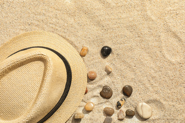 Fototapeta na wymiar Hat and pebbles on beach sand