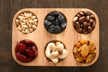 Wooden board with dried fruits and nuts on table, top view