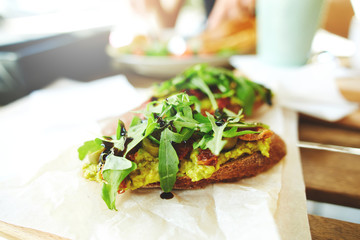 bruschetta with avocado, arugula, dried tomatoes and olives on a wooden table © vitaliymateha