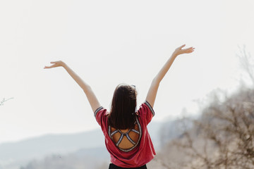 Fototapeta na wymiar happy stylish hipster woman standing on top of hill mountain and raising hands up, cheerful moment of happiness