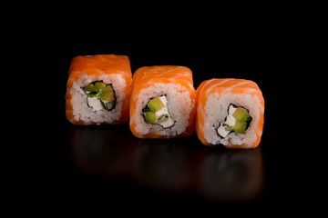 Japanese traditional food - sushi with avocado, rice, cottage cheese, salmon and green onion on the black background