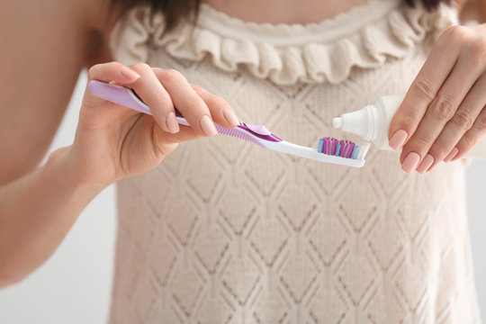 Young Woman Squeezing Toothpaste On Brush, Closeup