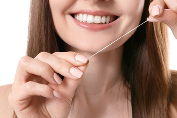 Young woman flossing her teeth on white background