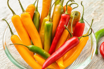 Glass bowl with fresh chili peppers on table, closeup