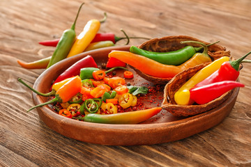 Plate with fresh chili peppers on wooden background