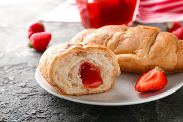 Tasty croissants with strawberry jam on plate, closeup