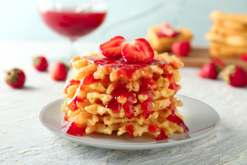 Plate with waffles and strawberry jam on wooden table