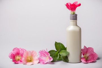 Bottle with cosmetic product and mallow flowers
