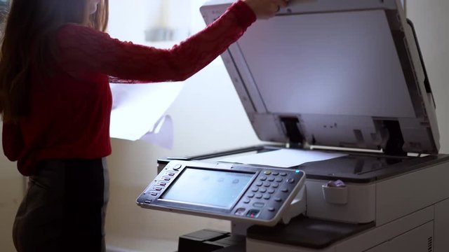 Businesswoman hands working in process press of paper in laser printer in the office. Girl printing Business Documents.