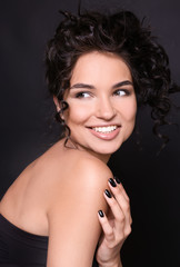 Fototapeta premium Fashionable young woman with black manicure on dark background