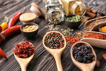 Spoons with different dry spices on wooden  background