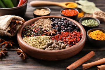 Bowls with different dry spices on wooden background