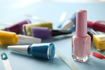 Bottles of varnish and artificial nails on color background