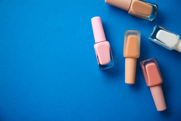 Bottles of nail polishes on color background