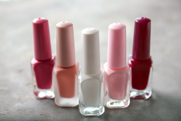 Bottles of colorful nail polishes on grey background