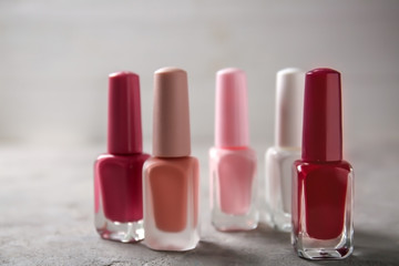 Bottles of colorful nail polishes on grey background