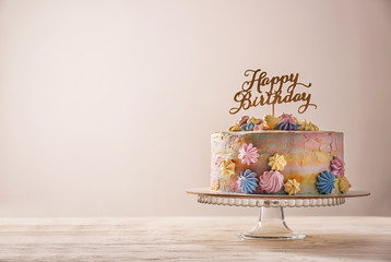 Stand with delicious birthday cake on table against light background
