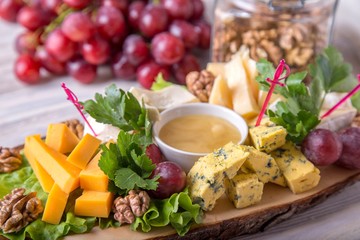 Cheese plate served with nuts and honey on wooden board