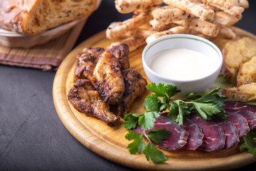 Tasty beer snack: fried chicken wings, basturma,  sandwiches with capelin caviar and   bread sticks with sauce. on wooden board. Copyspace