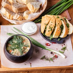 Mushroom soup in a pot with garlic bread and green onion
