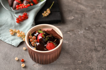 Bowl with tasty chocolate dipped strawberries on grey table