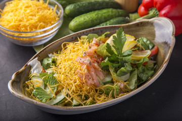 Salted salmon with vegetables and yellow cheese. Salad with salmon