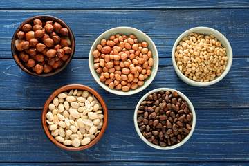 Bowls with different tasty nuts on wooden background