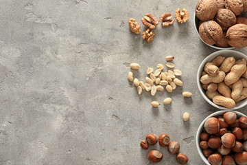 Bowls with different tasty nuts on light background