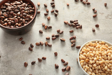 Bowls with tasty pine nuts on light background
