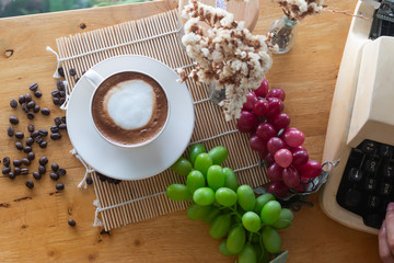 hot coffee in cup and coffee bean and typewriter and Grape fruit on the wooden table
