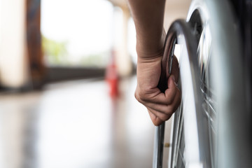 closeup disabled man hand on wheel of wheelchair - obrazy, fototapety, plakaty