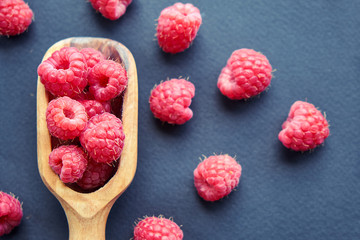 Fresh organic raspberries on black background. berries on a wooden spoon