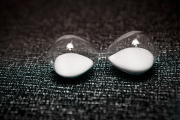 hourglass with white sand on dark background