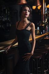 Obraz na płótnie Canvas elegant lady in black dress, in restaurant at a bar